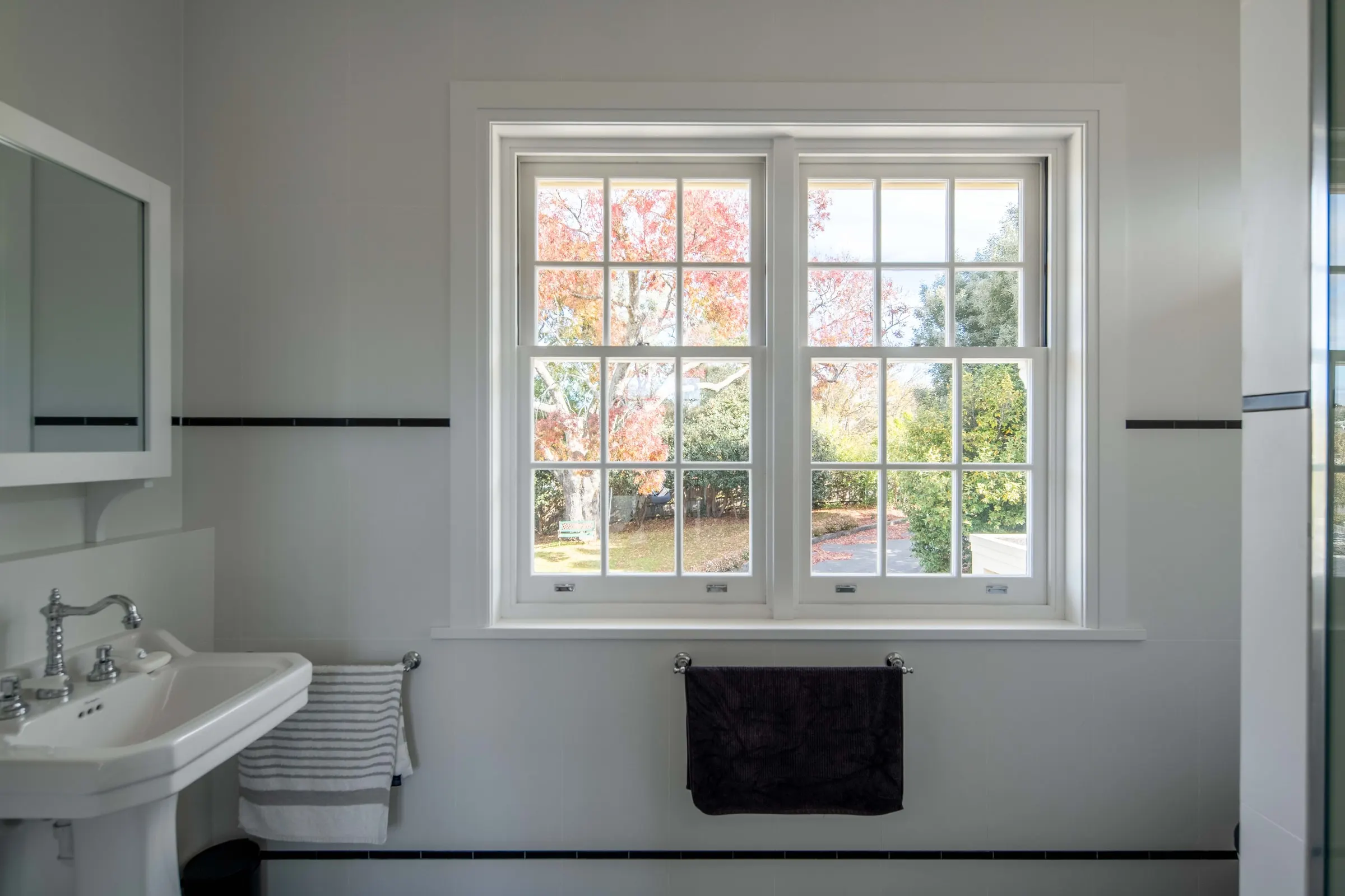 A finished bathroom with a pedestal basin and a double-hung window onto the garden, East Launceston