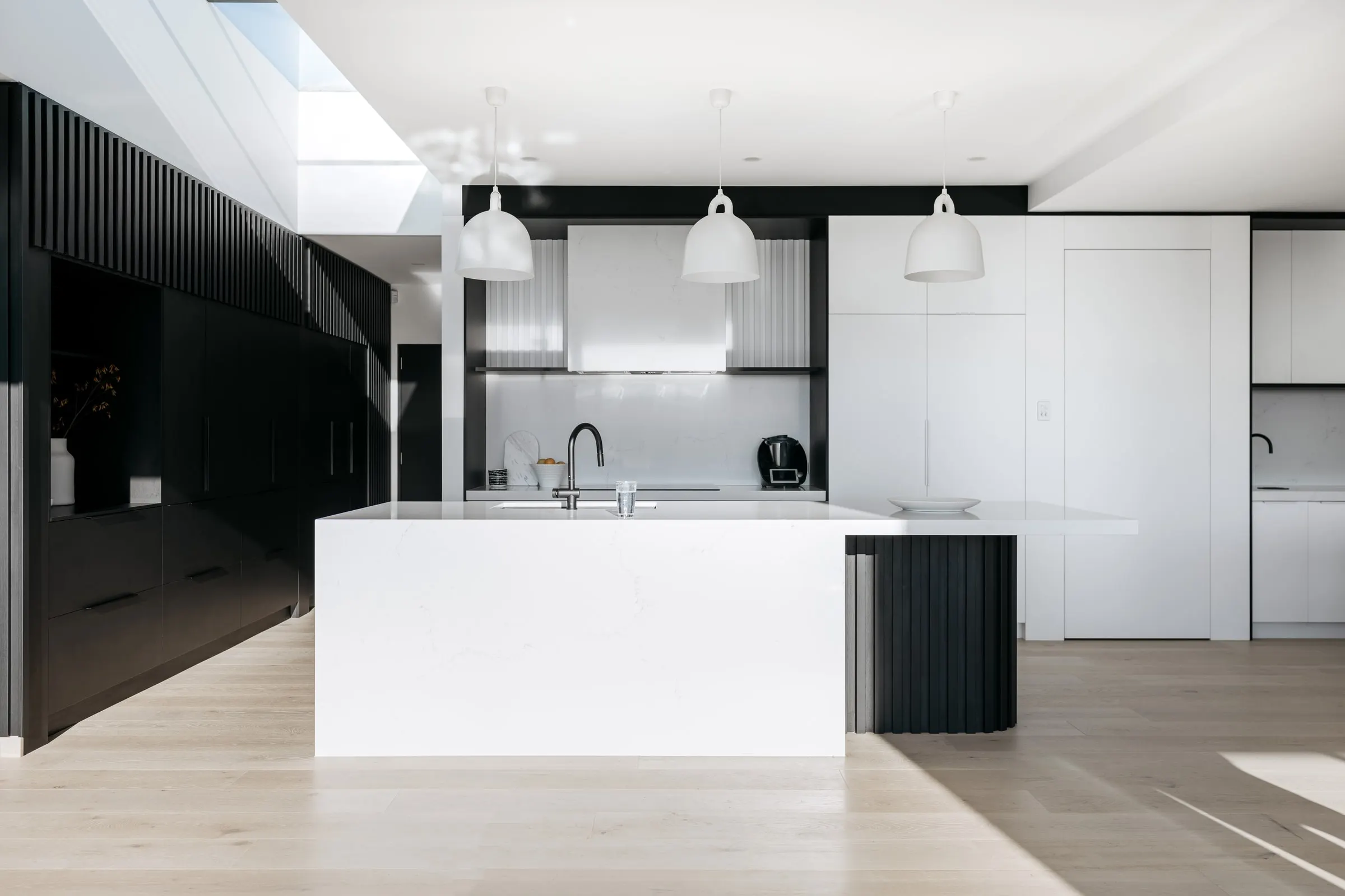A finished kitchen with dark joinery, a white island and pendant lights, Launceston