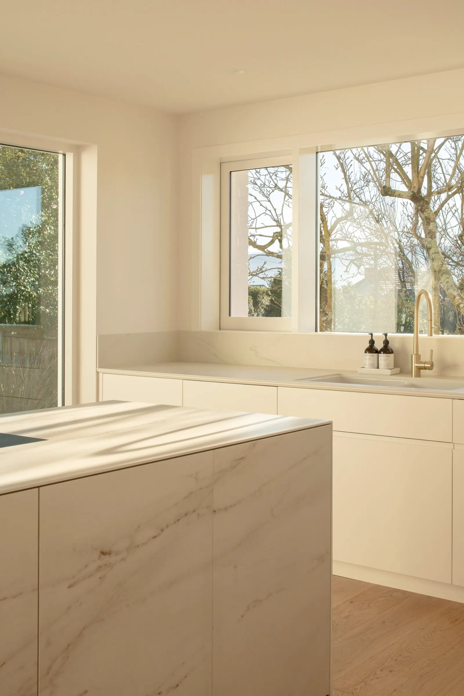Corner of a finished kitchen with a stone island and a window to the garden, Newstead