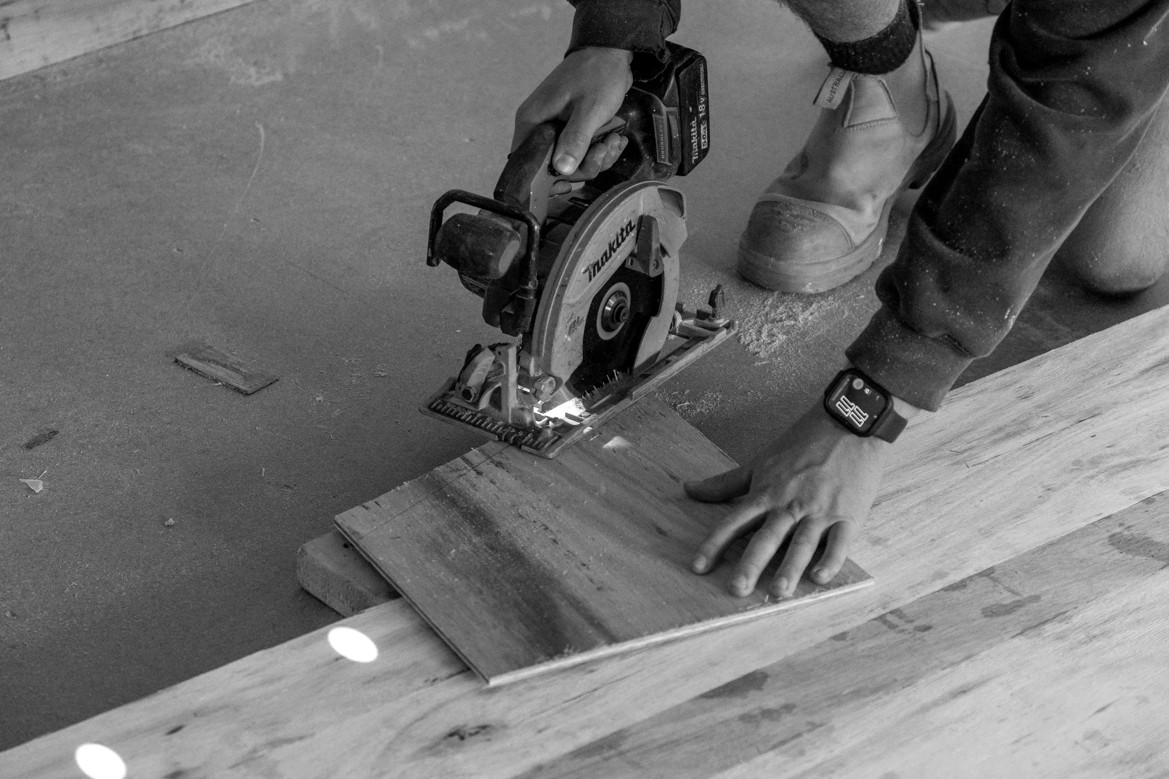 Hands guiding a circular saw through a board on site, frame stage, Relbia